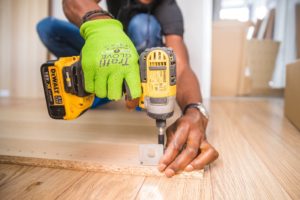 person-using-dewalt-cordless-impact-driver-on-brown-board